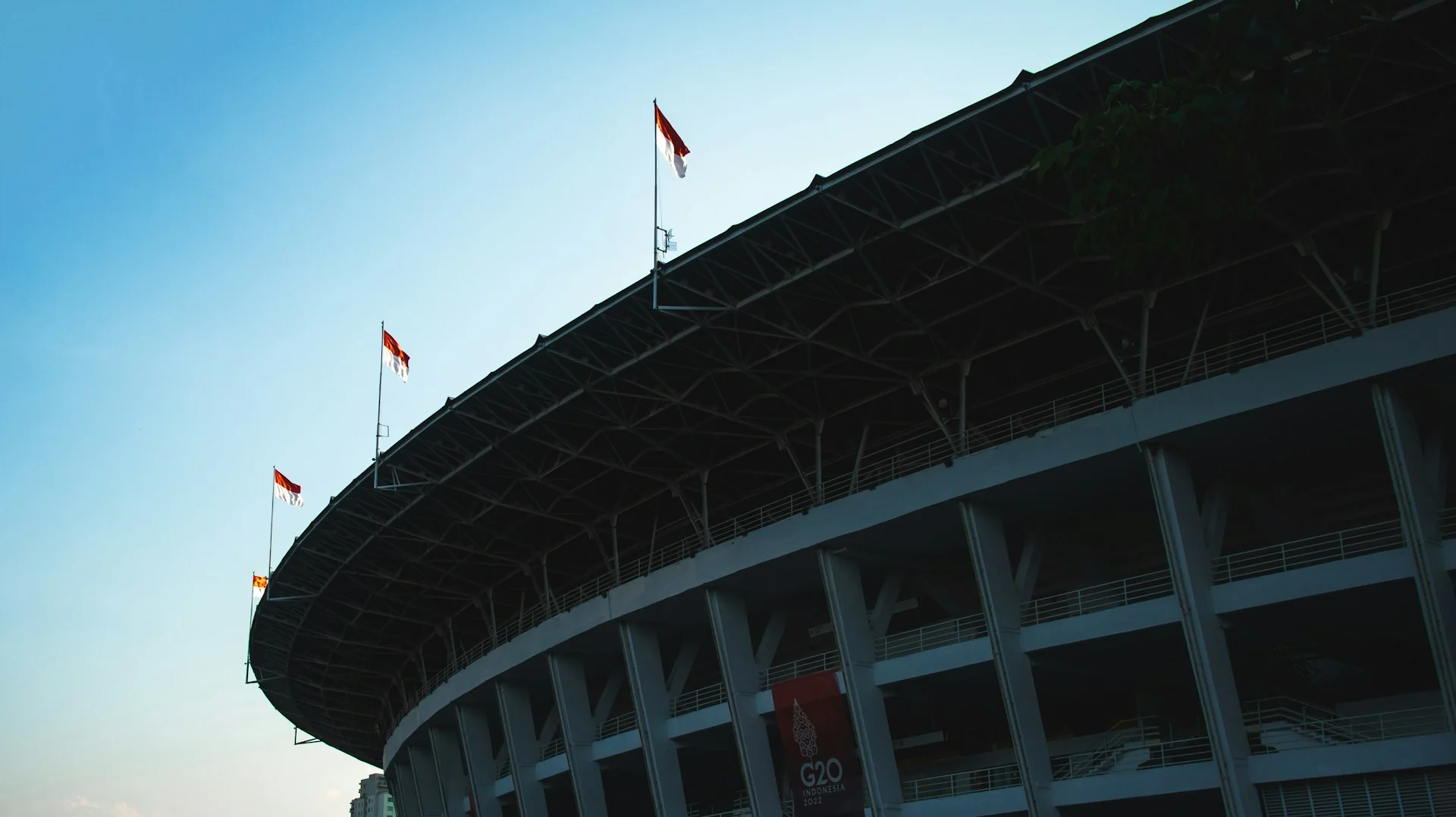 Atap melingkar dan pilar fasad Stadion Utama Gelora Bung Karno dengan bendera merah putih di tepi atap