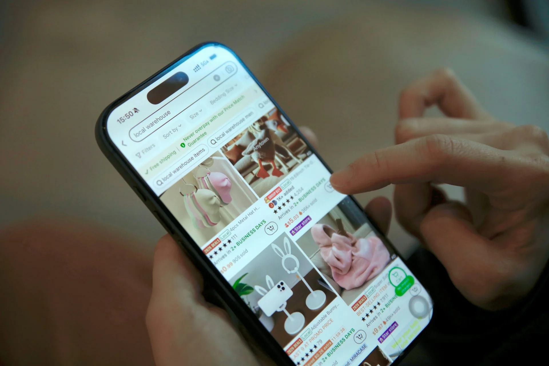 Tangan menggulir daftar produk diskon di aplikasi belanja daring pada ponsel