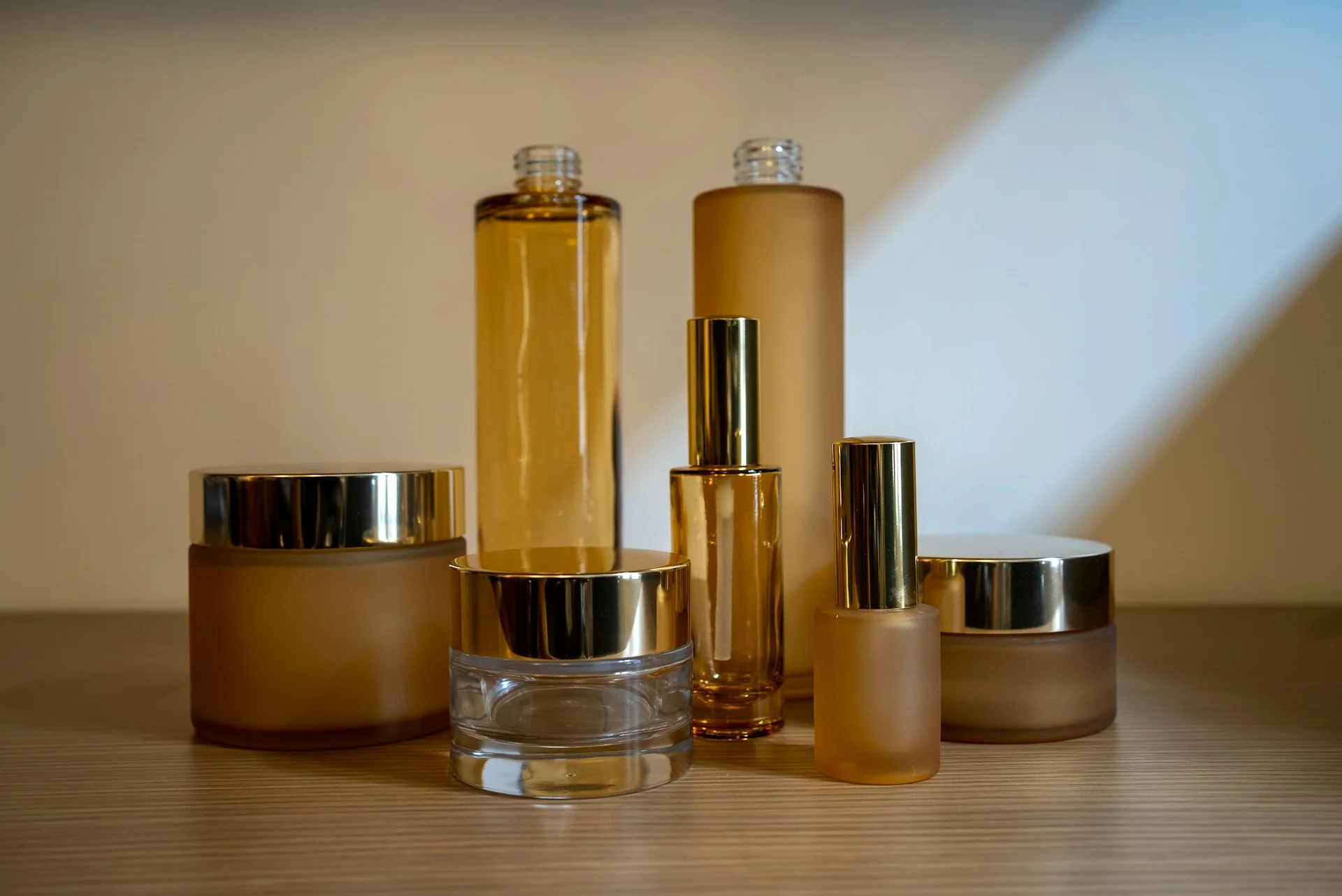 Deretan botol serum dan toples krim tanpa label di atas rak kayu