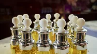 Deretan botol pipet kaca berisi cairan kuning dengan tutup perak dan pipet putih