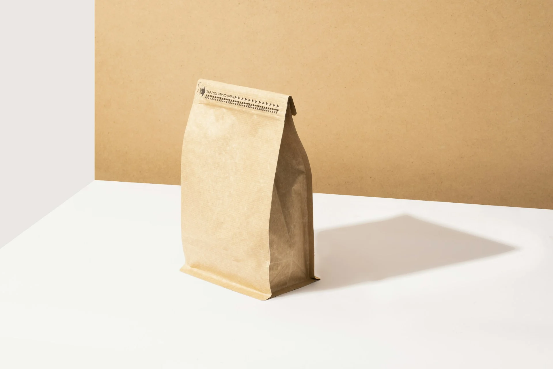 Kantong kemasan kertas kraft polos berdiri di meja putih dengan latar krem