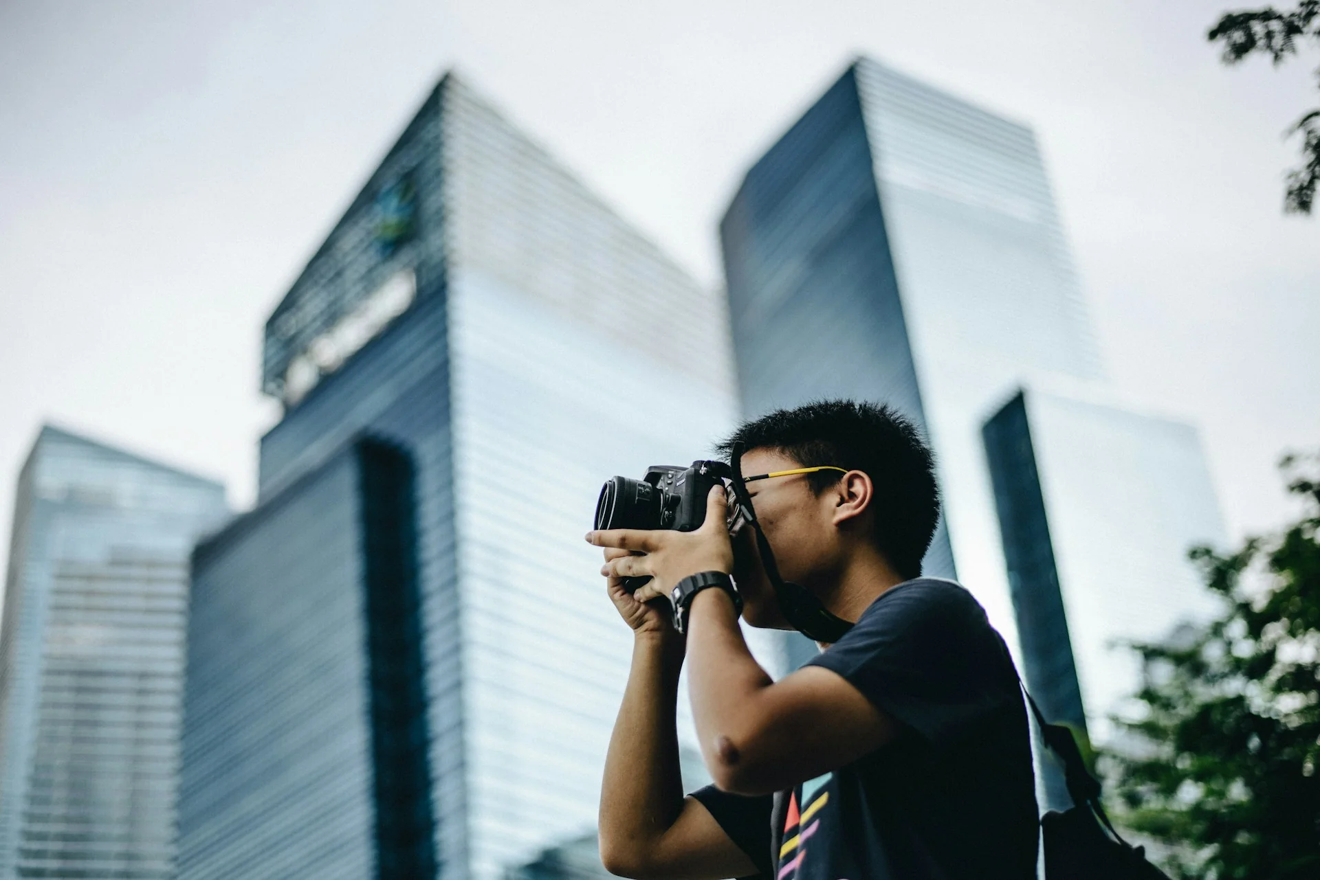 Pria memotret dengan kamera DSLR di antara gedung tinggi
