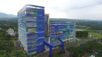 Foto udara gedung BCA Learning Institute bercorak biru dan hijau di tengah pepohonan
