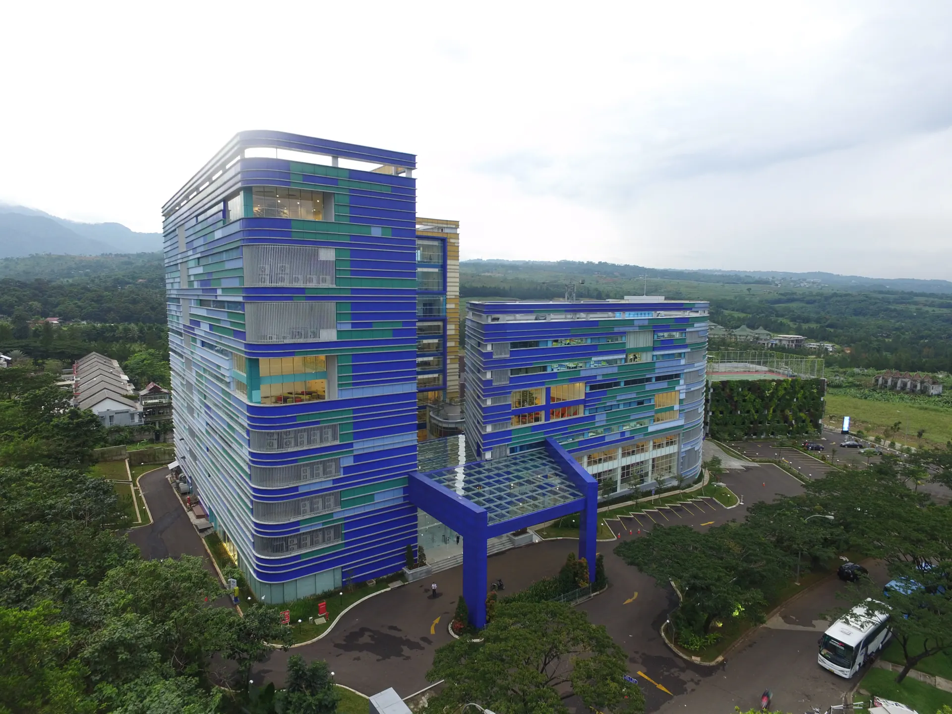 Foto udara gedung BCA Learning Institute bercorak biru dan hijau di tengah pepohonan
