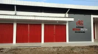 Gerai Koperasi Desa Merah Putih Desa Watualang dengan pintu rolling door merah dan papan nama Kopdes