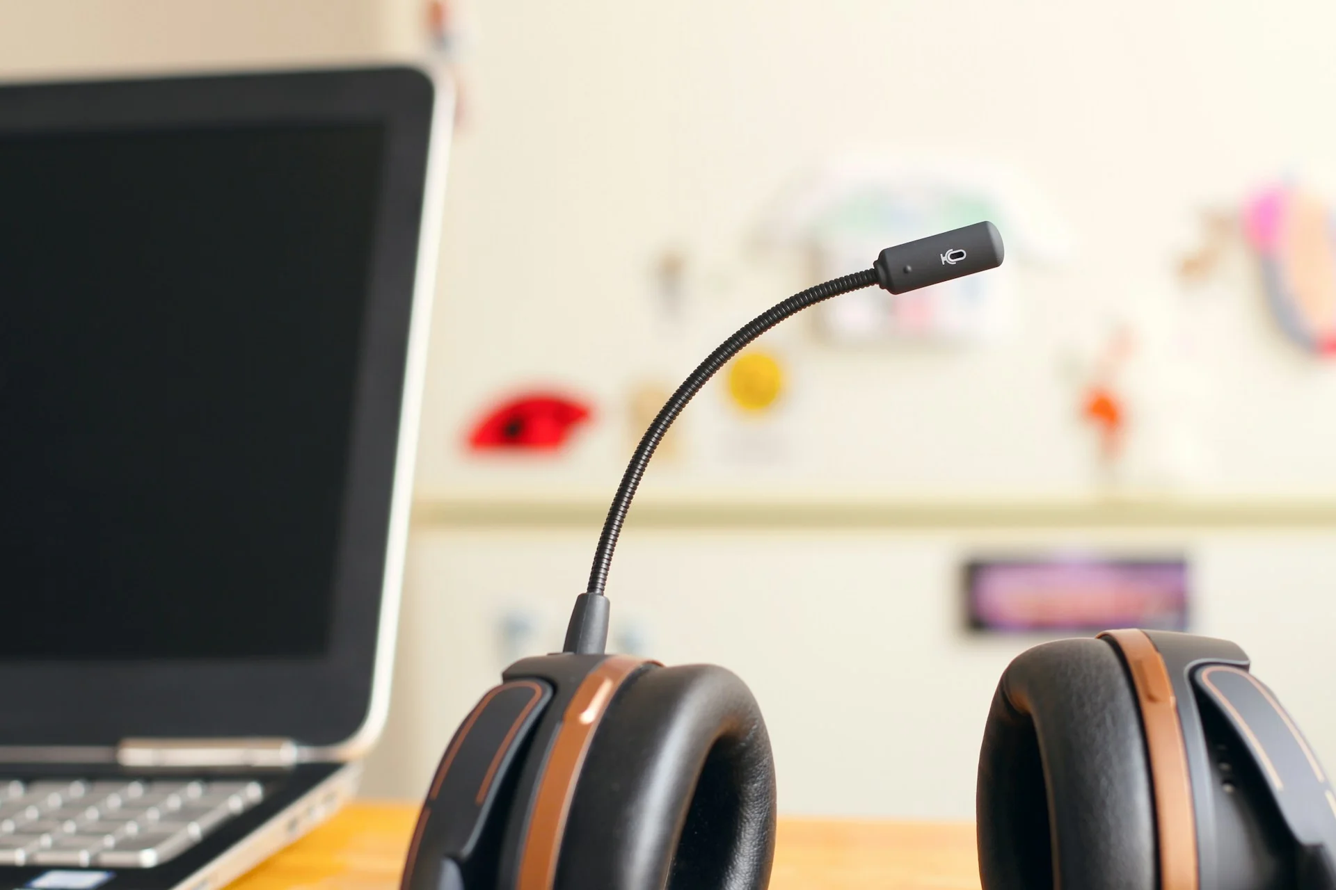 Headset bermikrofon di samping laptop di meja kerja