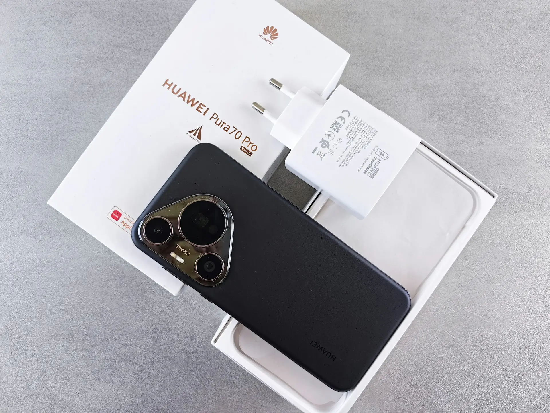 Smartphone baru diletakkan di atas kotak kemasan terbuka bersama charger