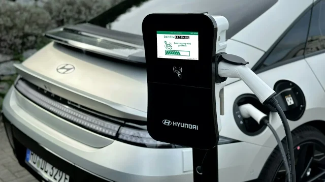 Hyundai Ioniq 6 putih sedang mengisi daya dengan kabel tercolok ke tiang charger AC