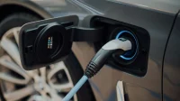 Kabel charger tercolok ke mobil listrik Kabel pengisian tercolok ke port charging mobil listrik abu-abu, ilustrasi biaya charging mobil listrik