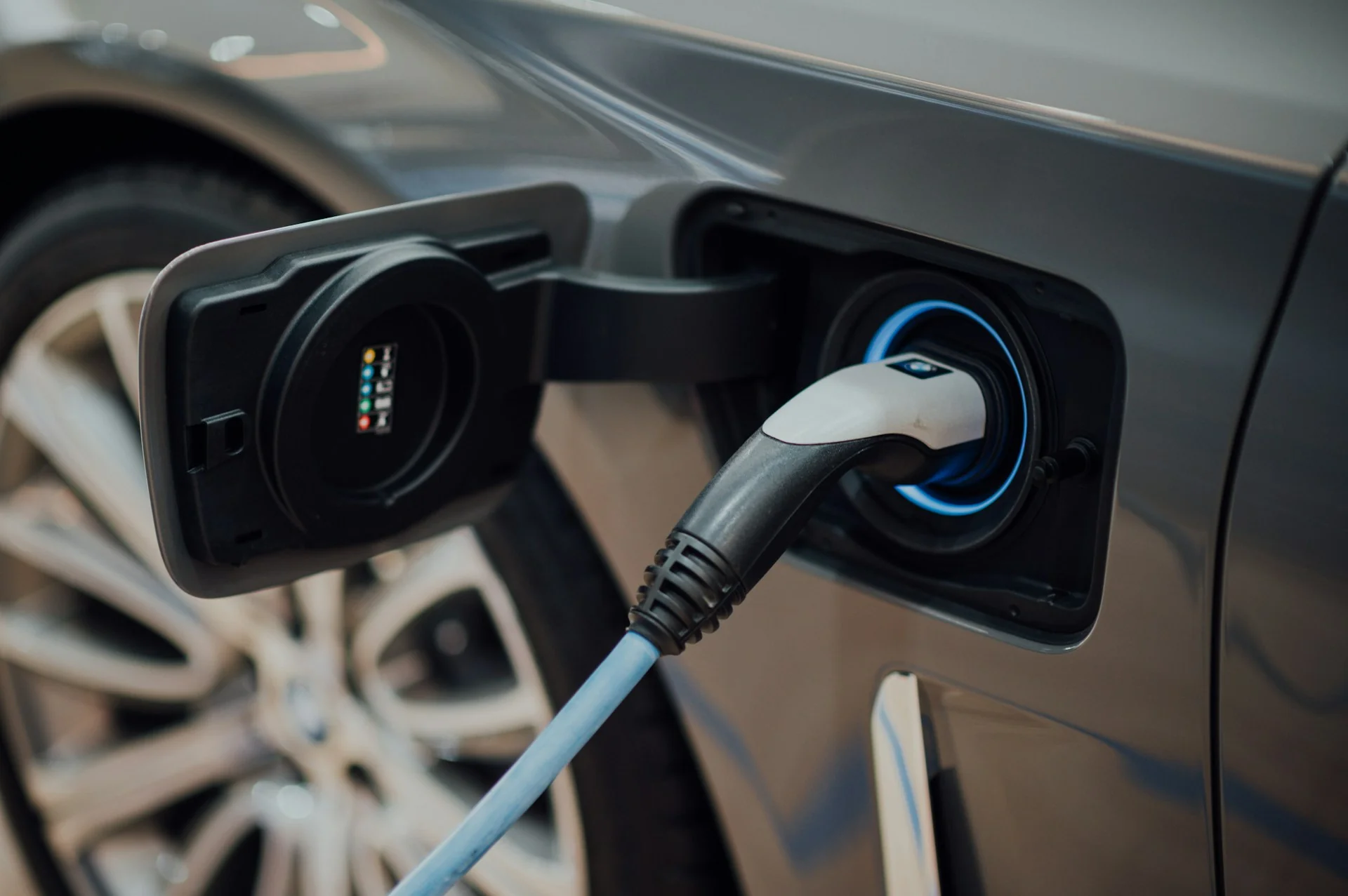 Kabel pengisian tercolok ke port charging mobil listrik abu-abu, ilustrasi biaya charging mobil listrik