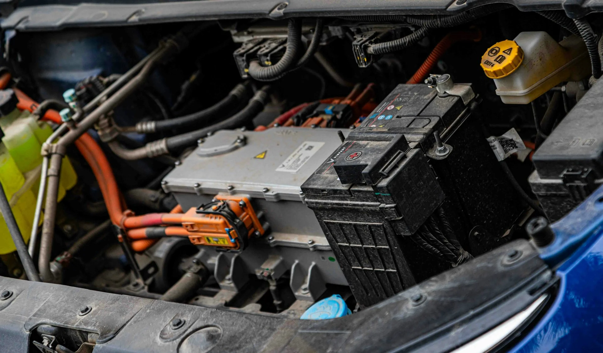 Kabel tegangan tinggi oranye, modul kelistrikan, dan aki 12 volt di ruang motor mobil listrik