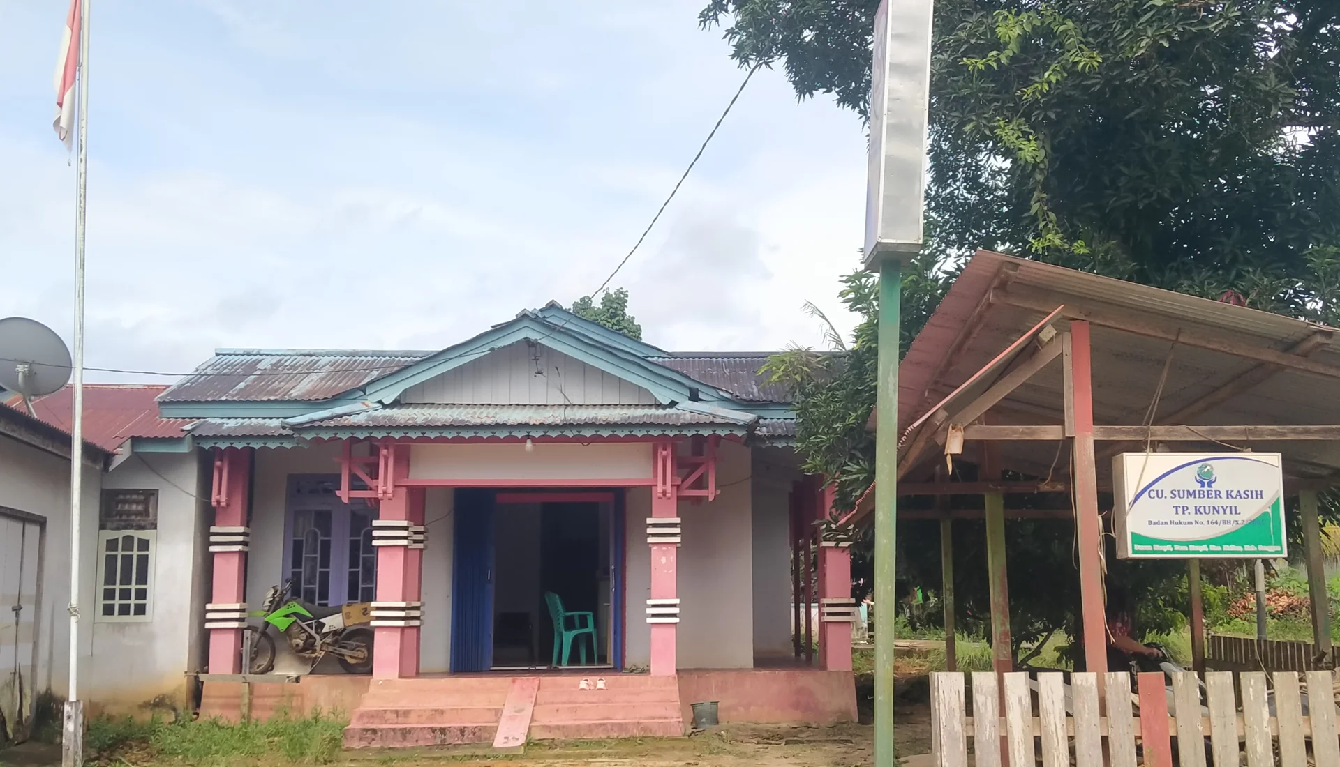 Kantor pelayanan Koperasi Simpan Pinjam CU Sumber Kasih TP Kunyil, bangunan satu lantai bertiang merah muda dengan papan nama di halaman