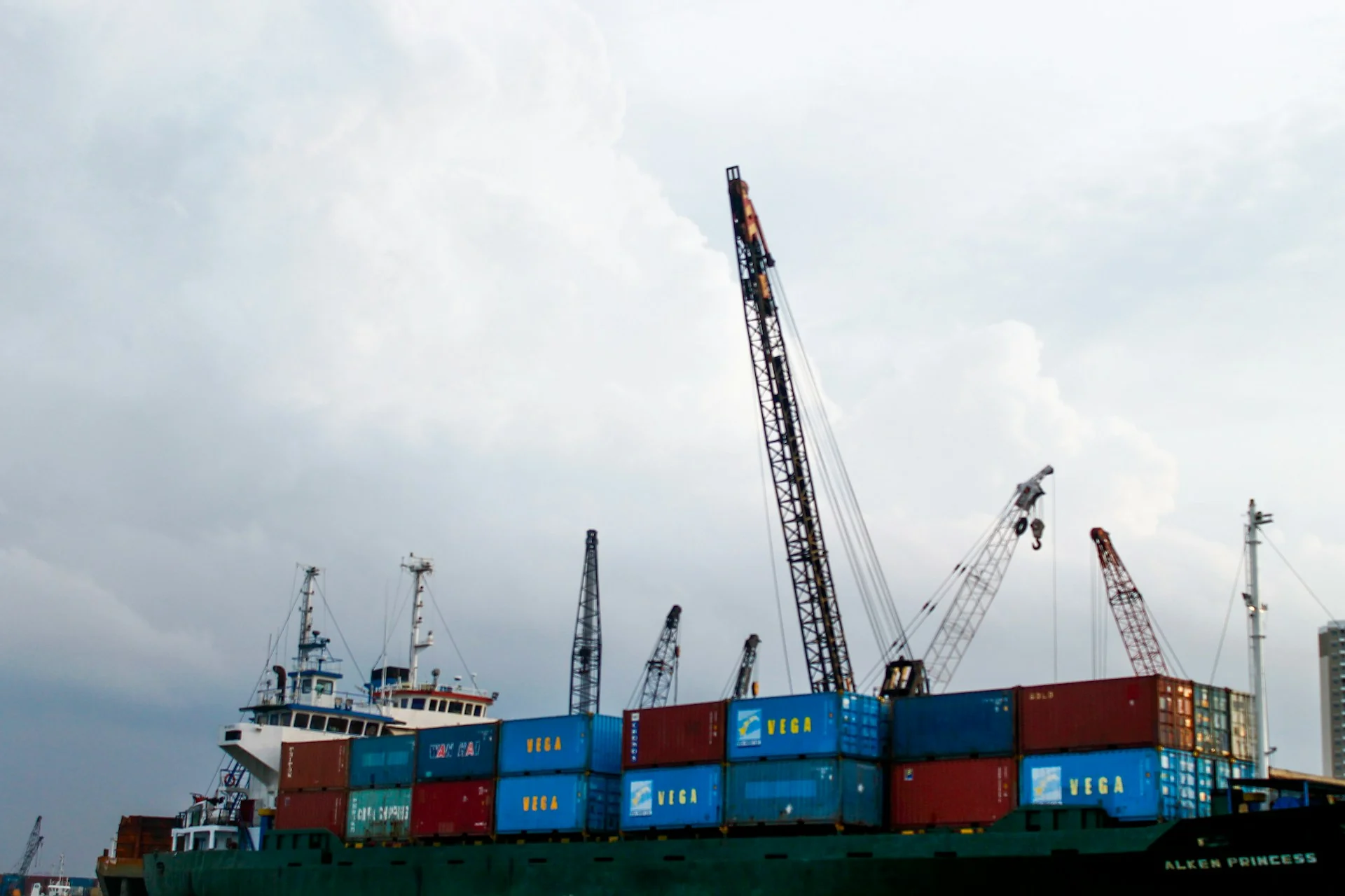 Kapal kargo bermuatan peti kemas dengan crane bongkar muat di pelabuhan Indonesia