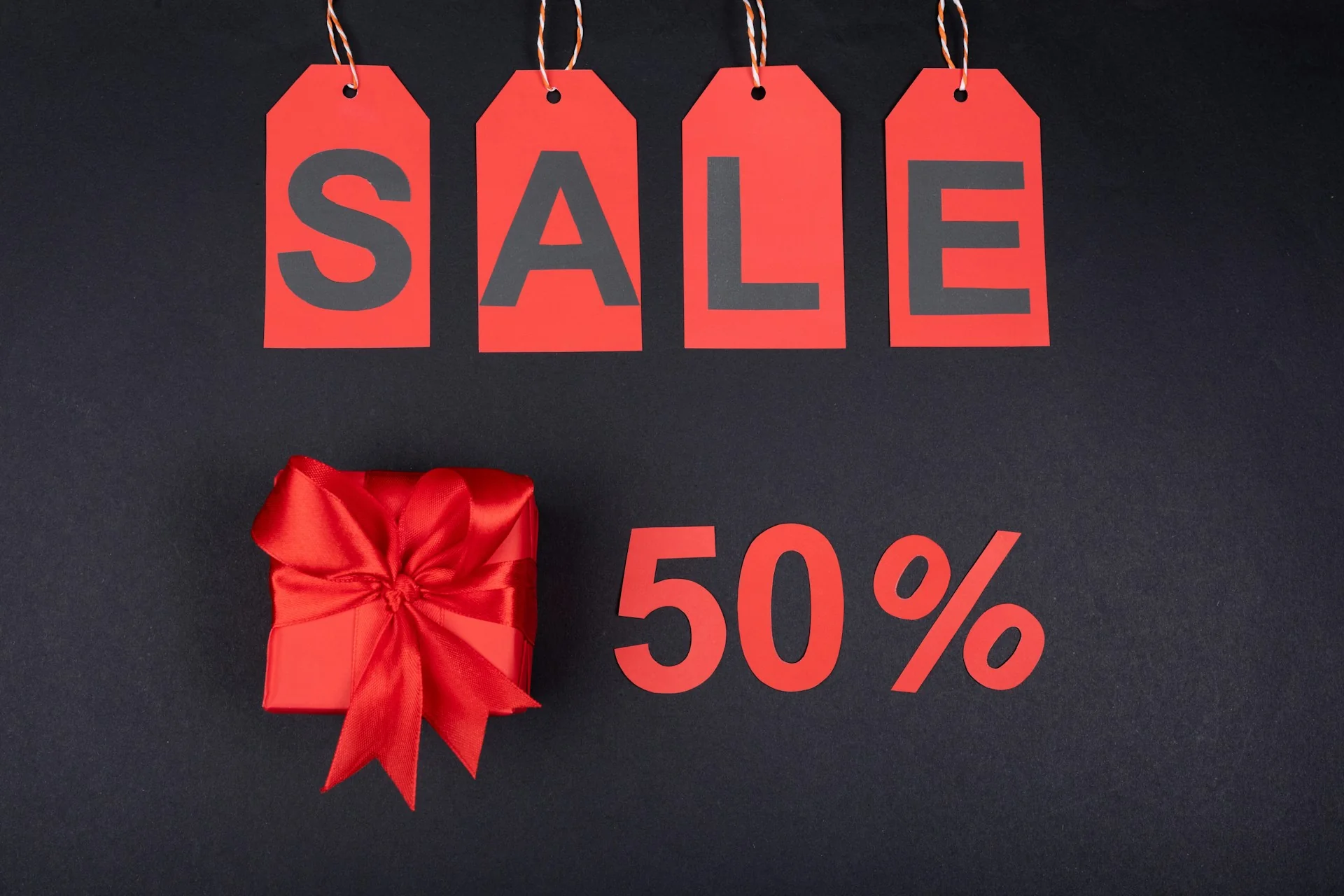 Label SALE merah dan angka diskon 50 persen di samping kotak kado