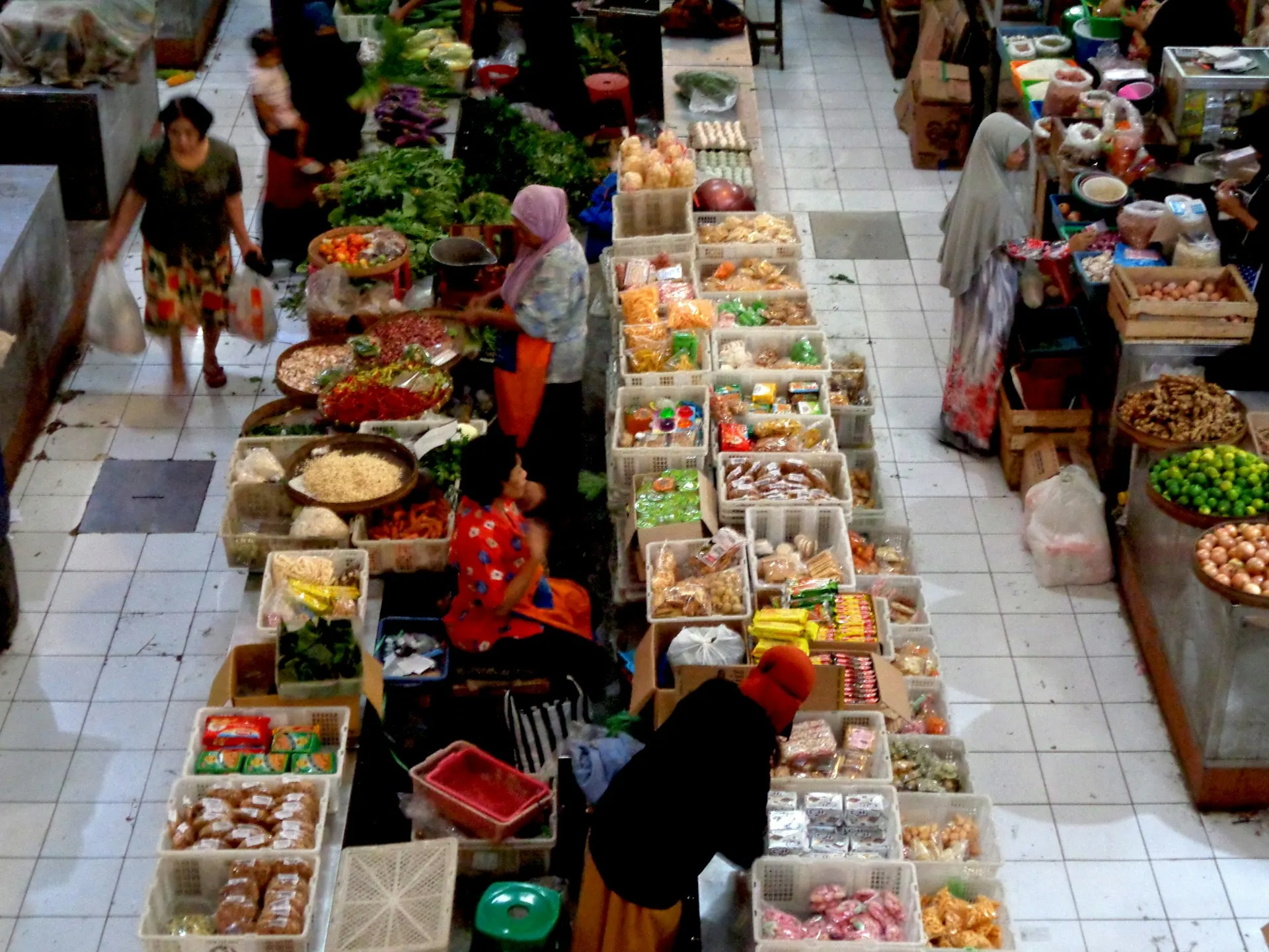 Lapak sayur, bumbu, beras, dan bahan pangan di lorong pasar tradisional dilihat dari atas