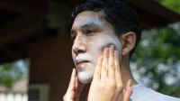 Pria meratakan krim tabir surya putih di wajah dengan jari saat berada di luar ruangan