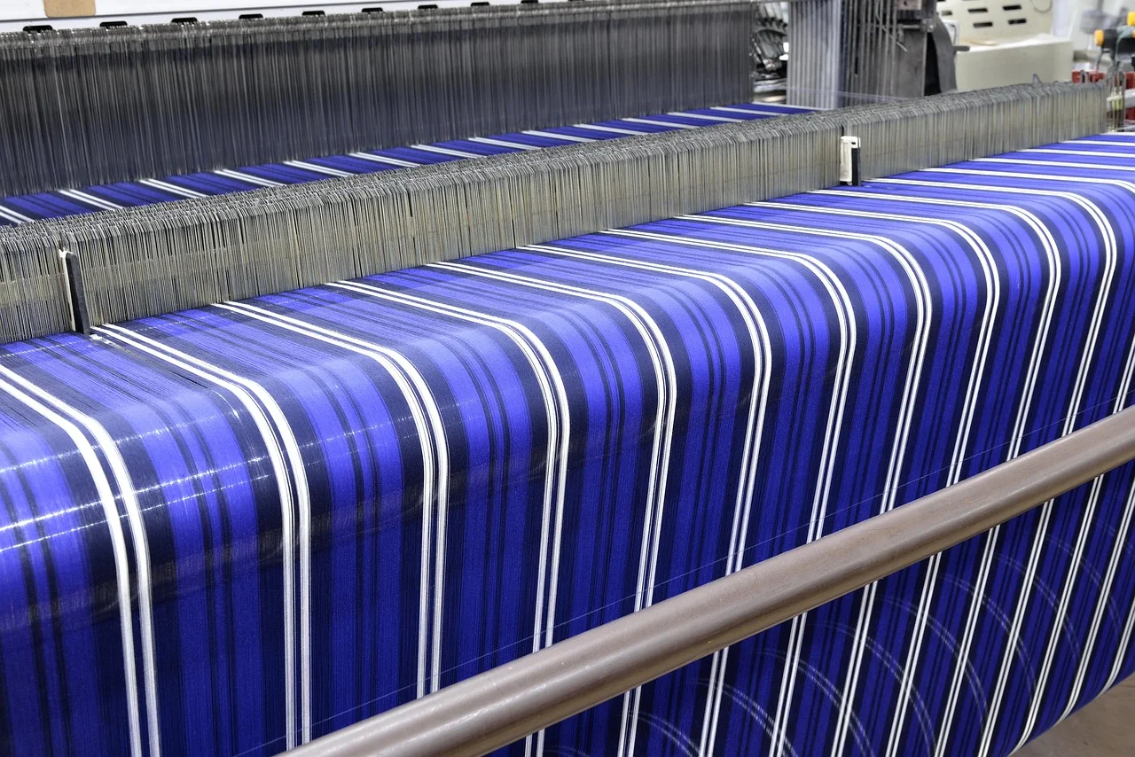 Mesin tenun otomatis menenun kain bergaris biru putih di lini produksi pabrik tekstil