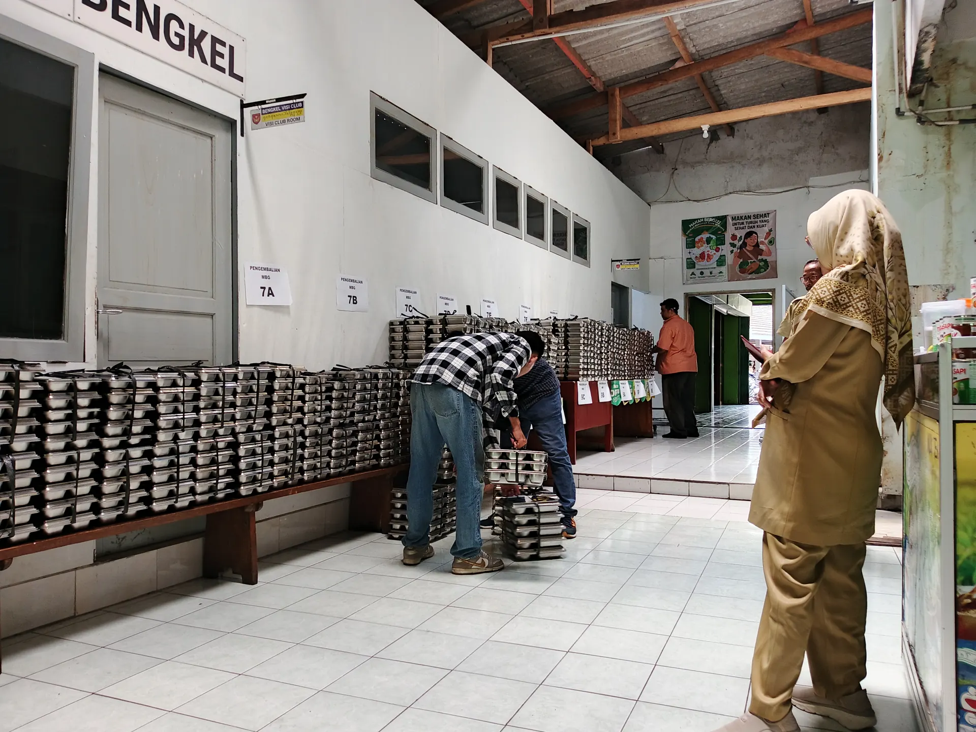 Tumpukan ompreng Makan Bergizi Gratis dijajarkan per kelas di lorong sekolah sementara petugas menyusun wadah