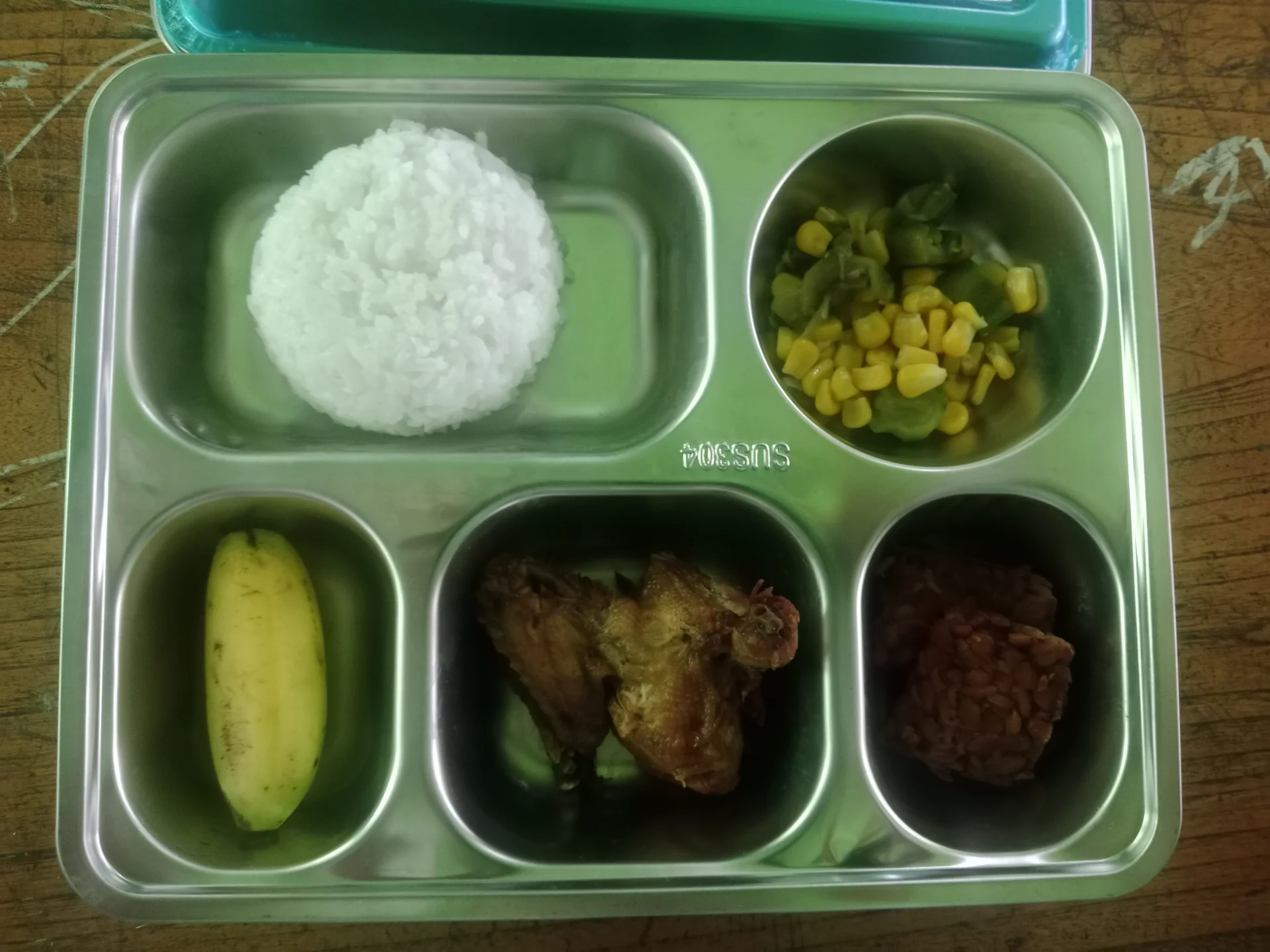 Ompreng baja tahan karat berisi nasi, tumis jagung dan sayur, ayam goreng, tempe, dan pisang menu Makan Bergizi Gratis