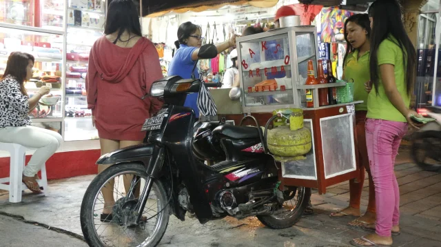 Pedagang soto bakso melayani pembeli dari gerobak motor di depan deretan toko di Kuta, Bali