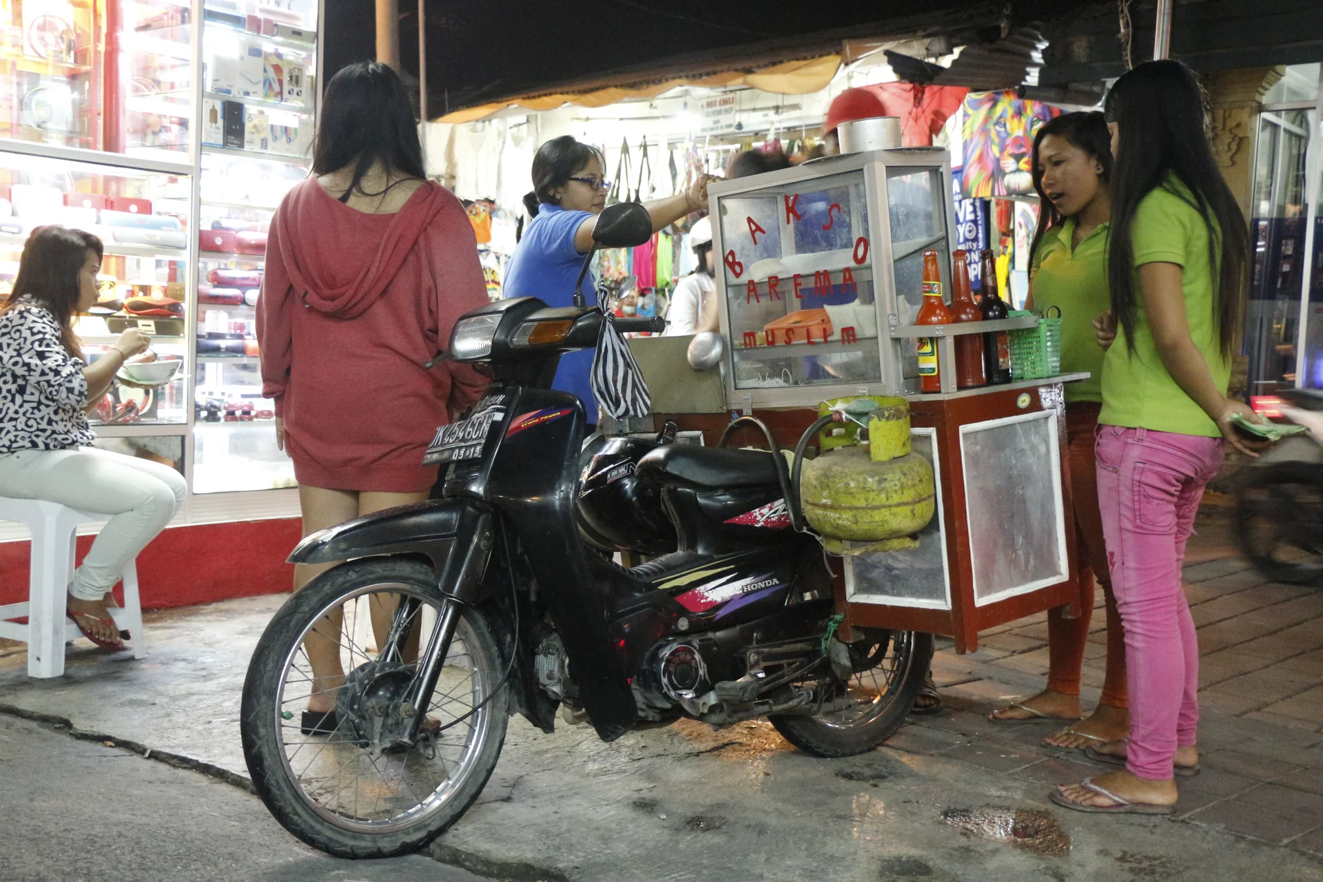 Pedagang soto bakso melayani pembeli dari gerobak motor di depan deretan toko di Kuta, Bali