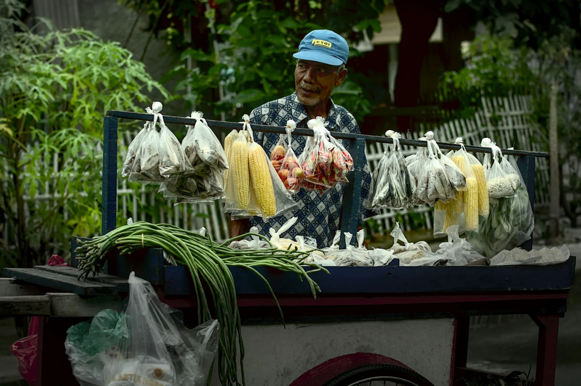 Pedagang sayur lanjut usia berdiri di balik gerobak berisi jagung dan kacang panjang, gambaran pelaku usaha kecil yang terdampak aturan pajak UMKM PP 20 Tahun 2026
