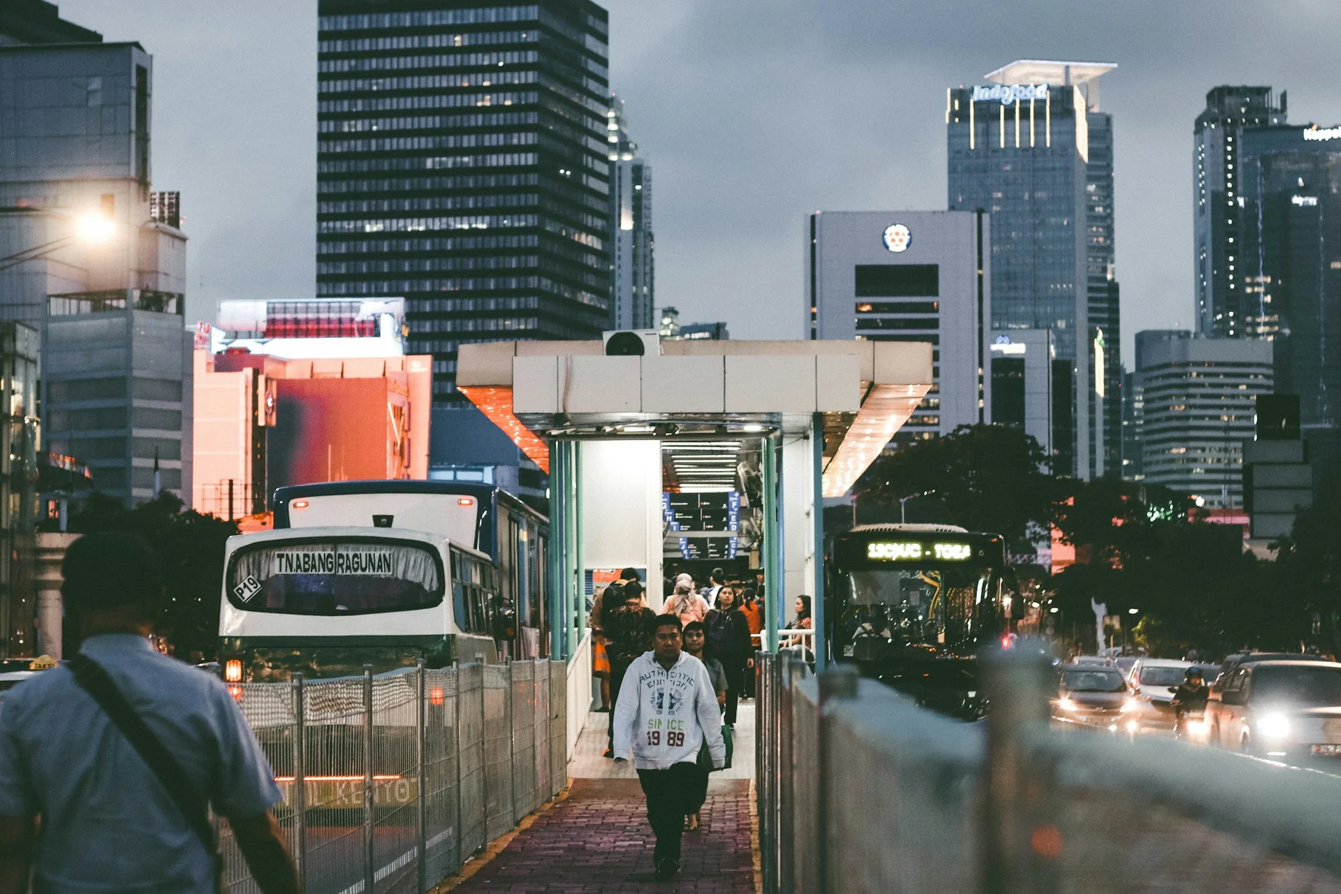 Pekerja berjalan keluar dari halte Transjakarta dengan latar gedung perkantoran Jakarta saat senja