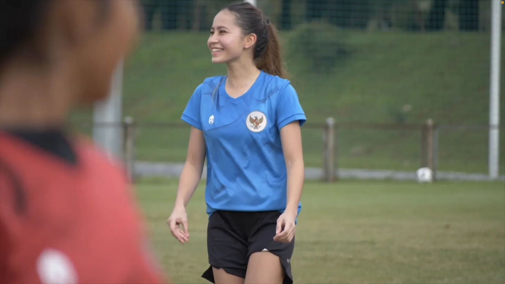 Pemain timnas putri Indonesia berkaus biru berlogo Garuda tersenyum saat sesi latihan di lapangan rumput
