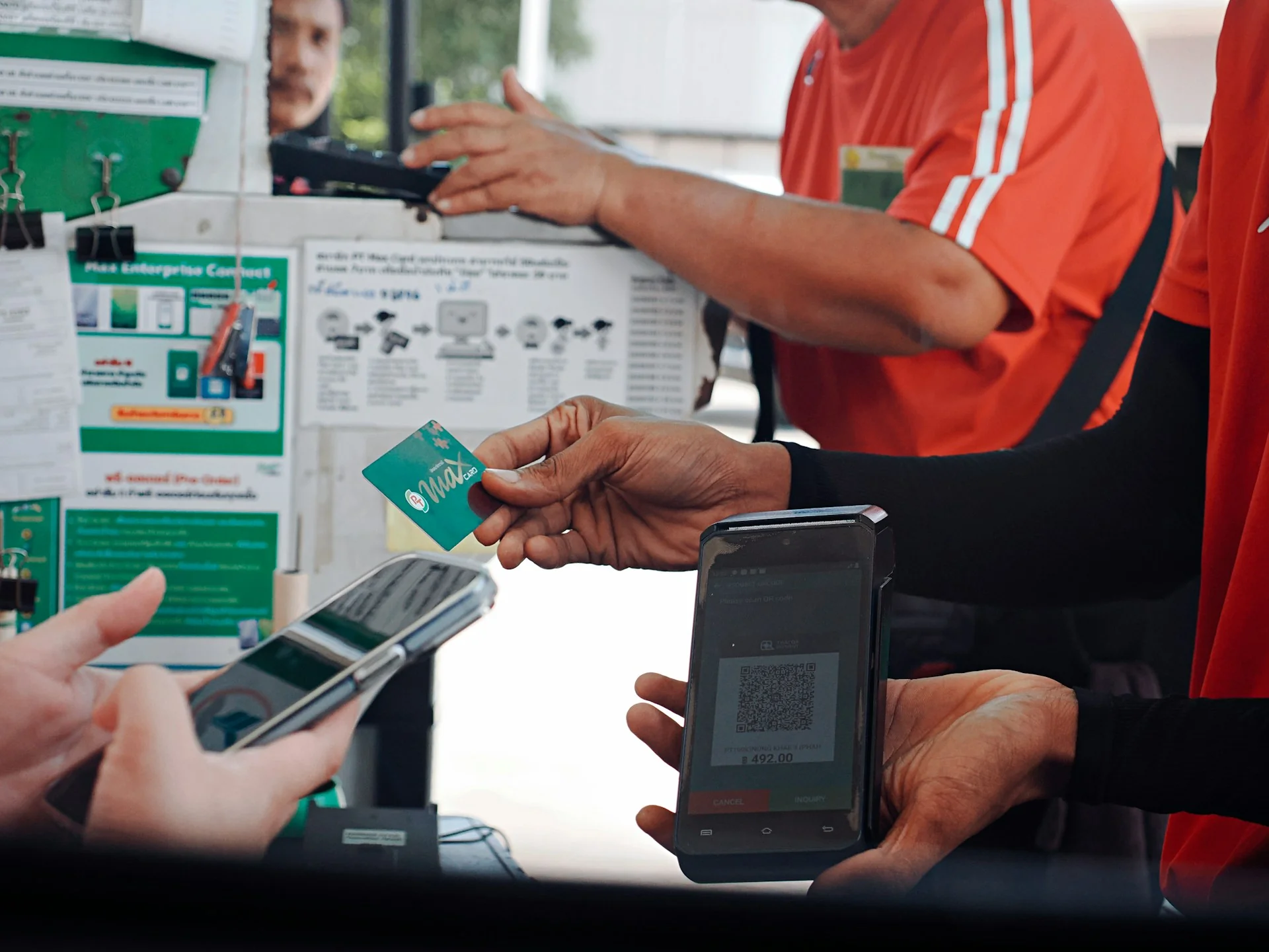 Petugas kasir menyodorkan perangkat genggam berisi kode QR sementara pembeli menyiapkan ponsel untuk membayar