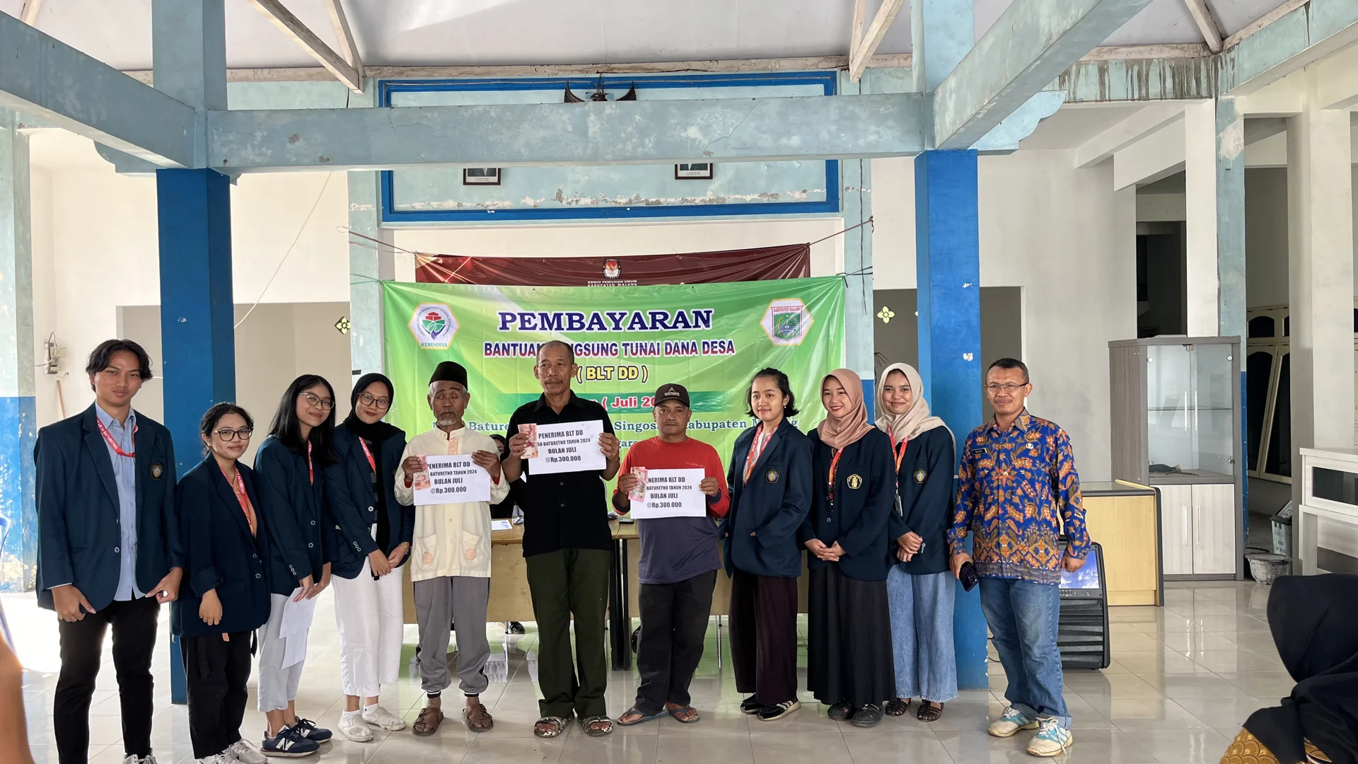 Warga penerima BLT Dana Desa memegang papan nominal bantuan di balai Desa Baturetno, Malang