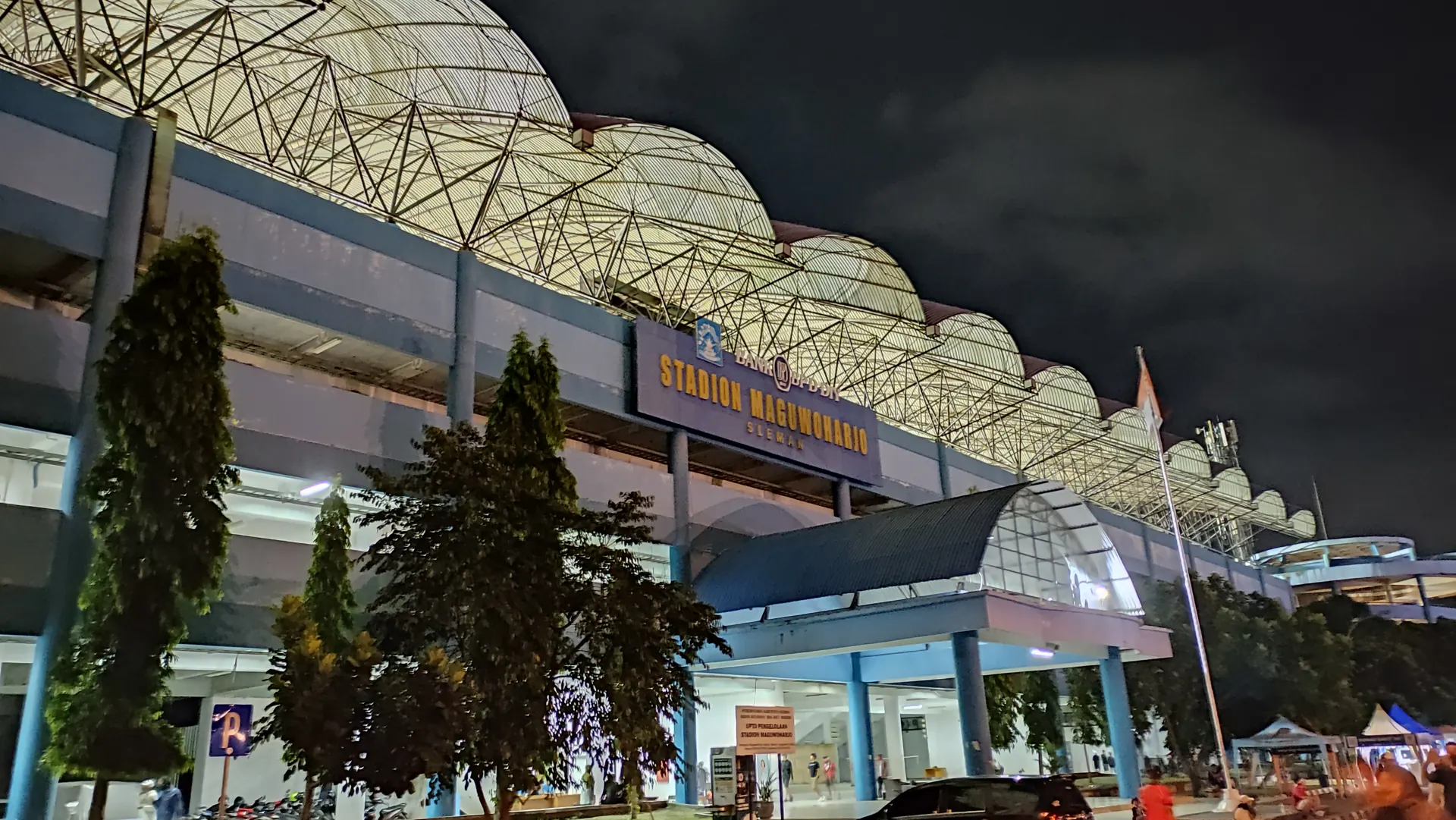 Pintu masuk utama Stadion Maguwoharjo Sleman pada malam hari dengan papan nama stadion