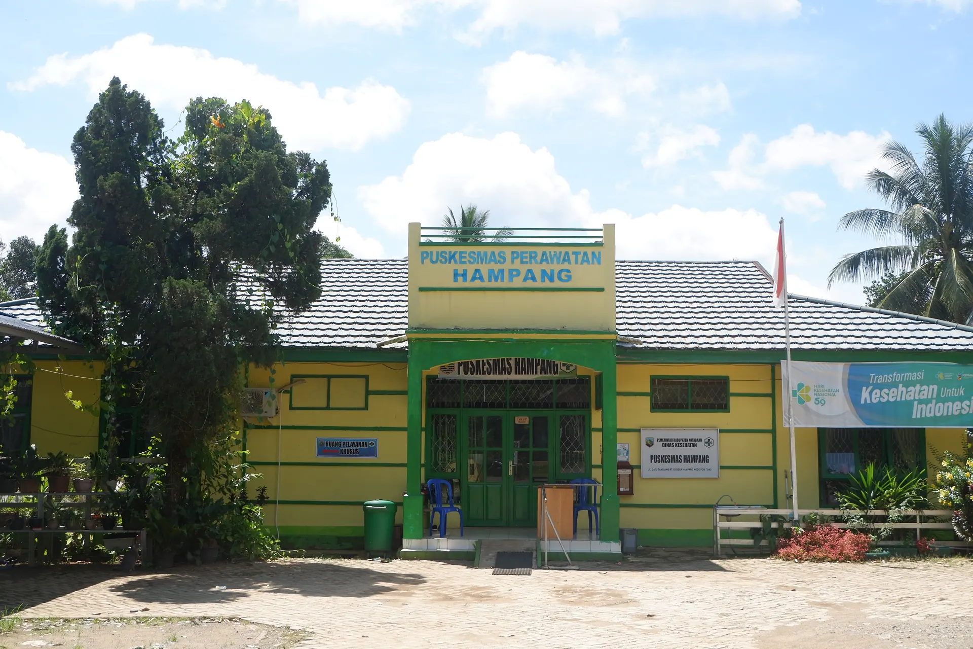 Gedung Puskesmas Perawatan Hampang bercat kuning hijau dengan spanduk Transformasi Kesehatan untuk Indonesia