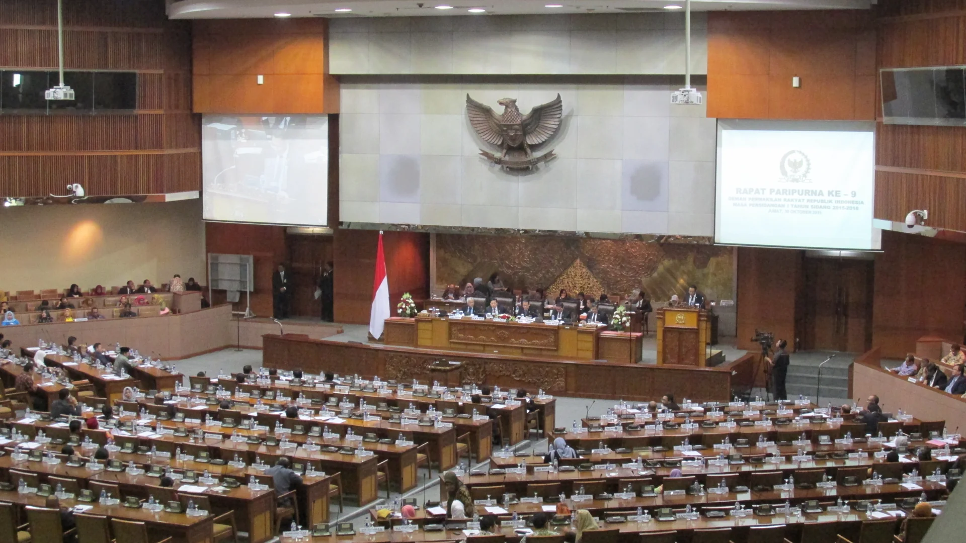 Suasana rapat paripurna DPR RI di ruang sidang Nusantara II dengan lambang Garuda di dinding pimpinan