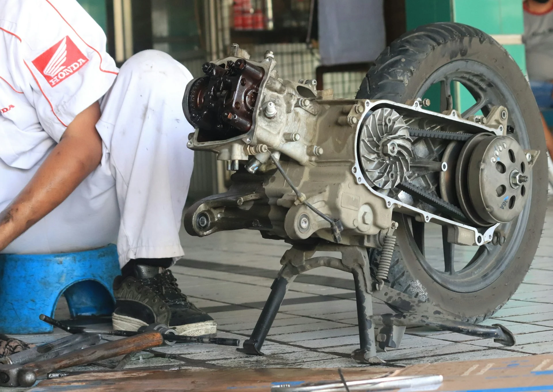 Mekanik memeriksa mesin skuter matik di bengkel