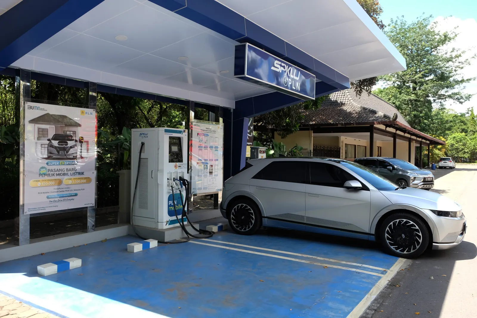 Hyundai Ioniq 5 perak terparkir di samping mesin pengisian SPKLU PLN beratap biru