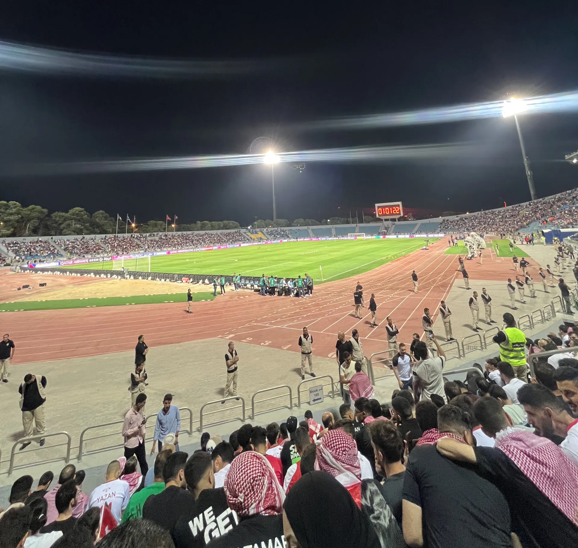 Suasana malam di dalam Stadion Internasional Amman dengan lampu sorot menyala dan tribune penuh penonton