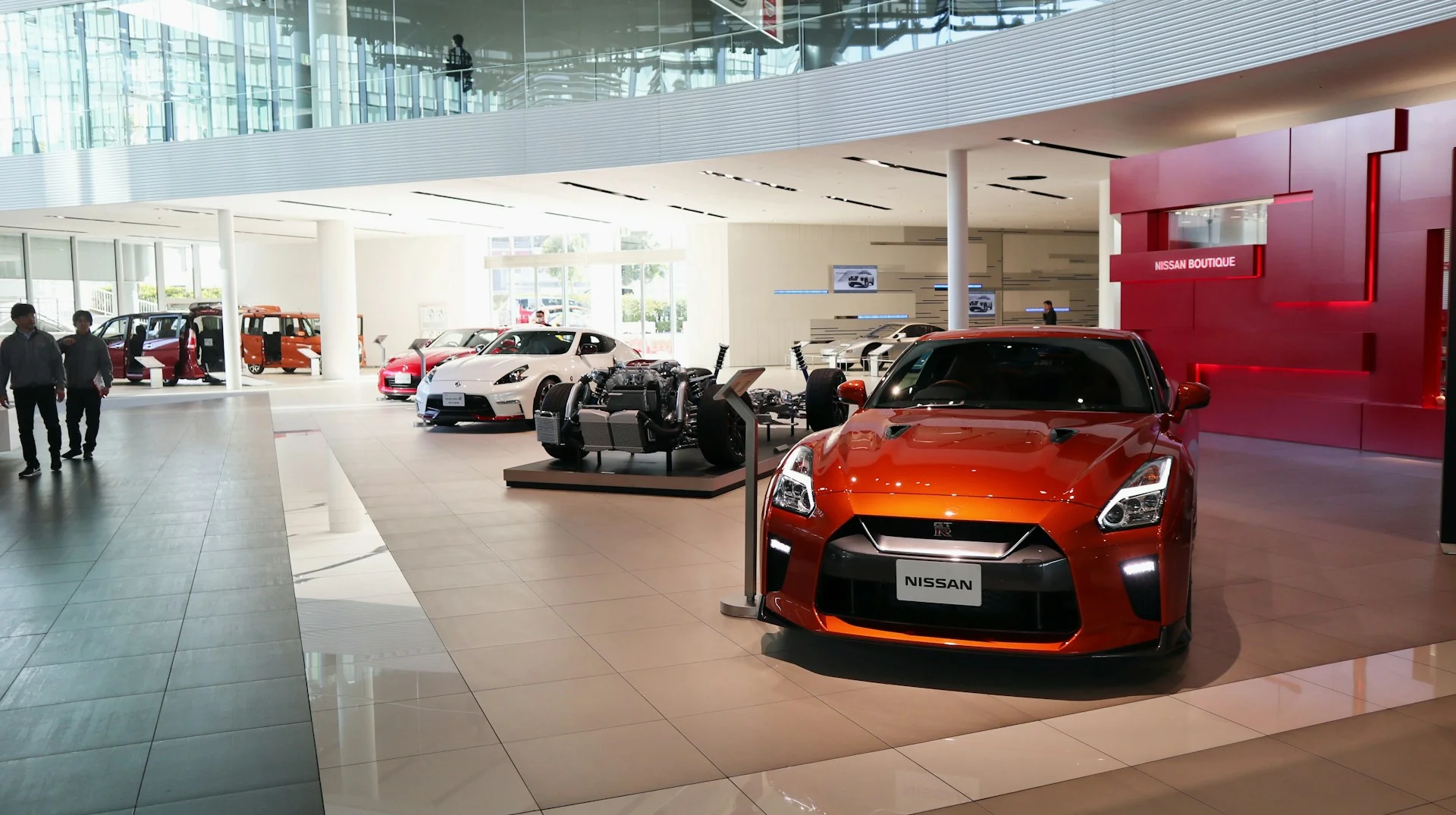 Suasana showroom mobil dengan deretan mobil dipajang dan pengunjung berjalan di lantai pameran