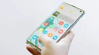 Tangan memegang smartphone Android dengan layar beranda menyala