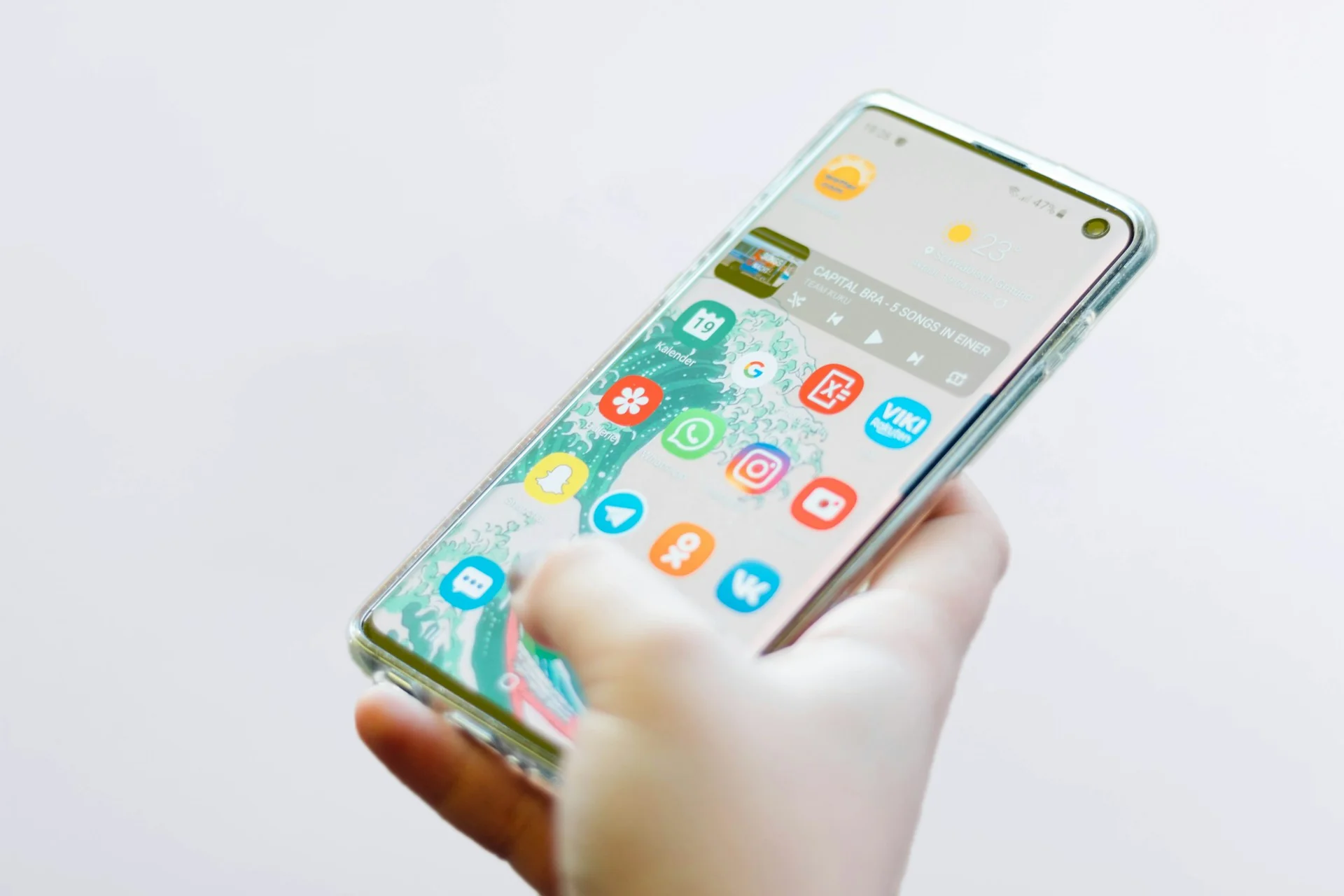 Tangan memegang smartphone Android dengan layar beranda menyala