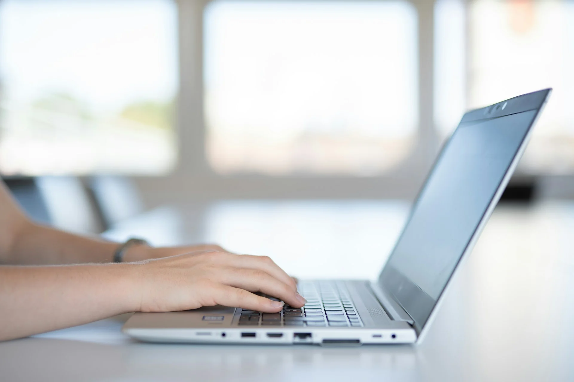Tangan seseorang mengetik di laptop saat mengisi formulir daring