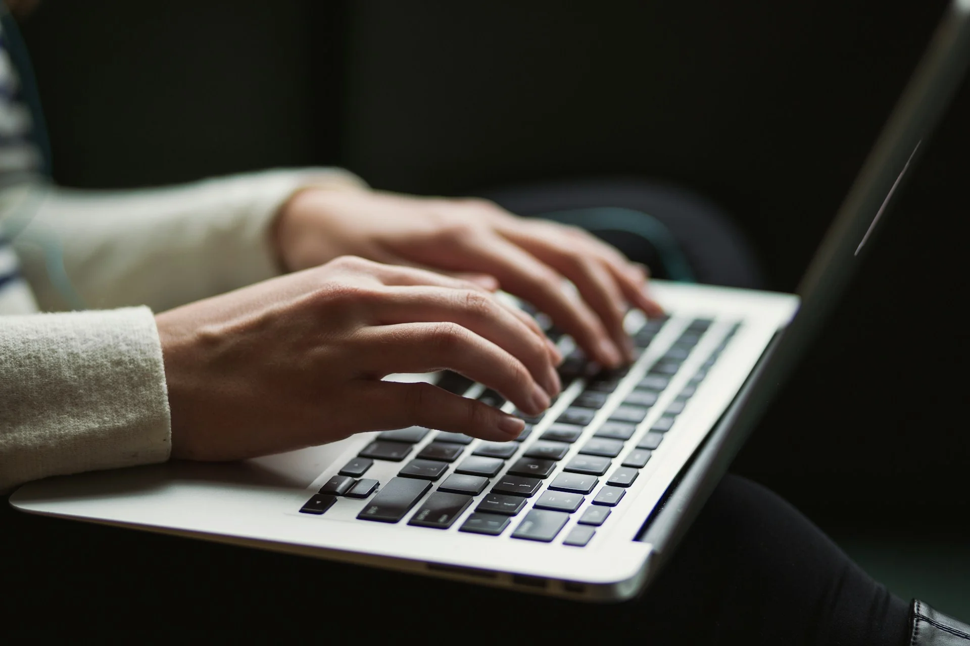 Dua tangan mengetik draf teks jualan online di laptop berwarna perak