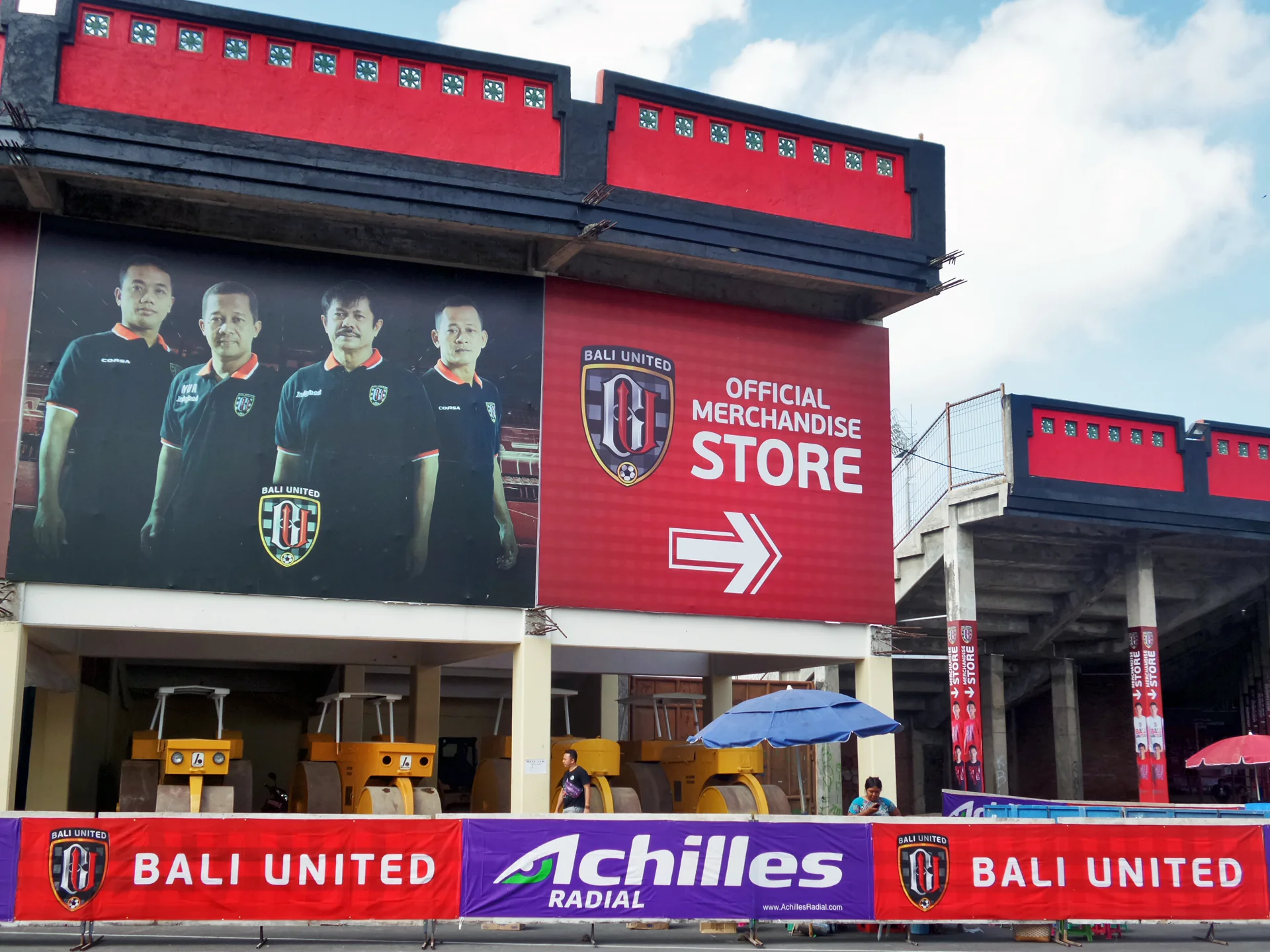 Papan Bali United Official Merchandise Store dan spanduk sponsor di bangunan Stadion Kapten I Wayan Dipta