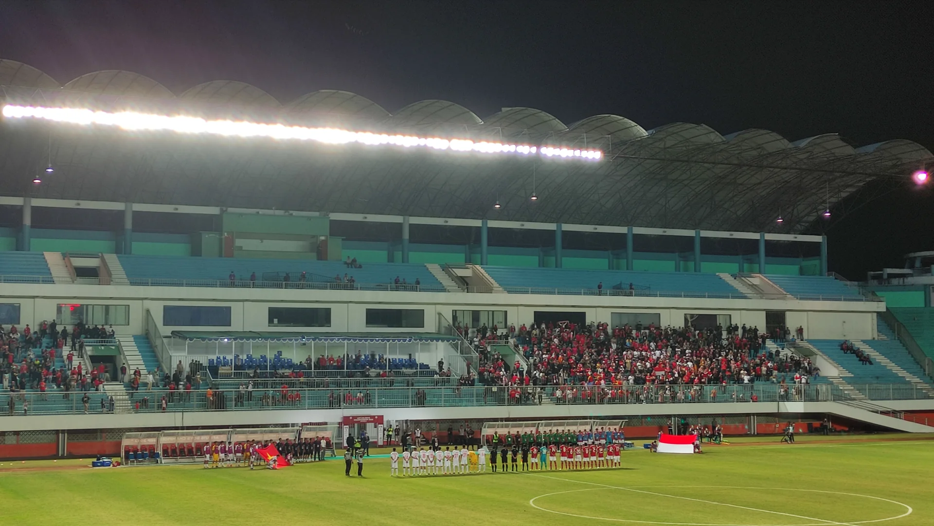Tribun Stadion Maguwoharjo Sleman terisi penonton pada malam hari saat pemain berbaris di lapangan sebelum laga