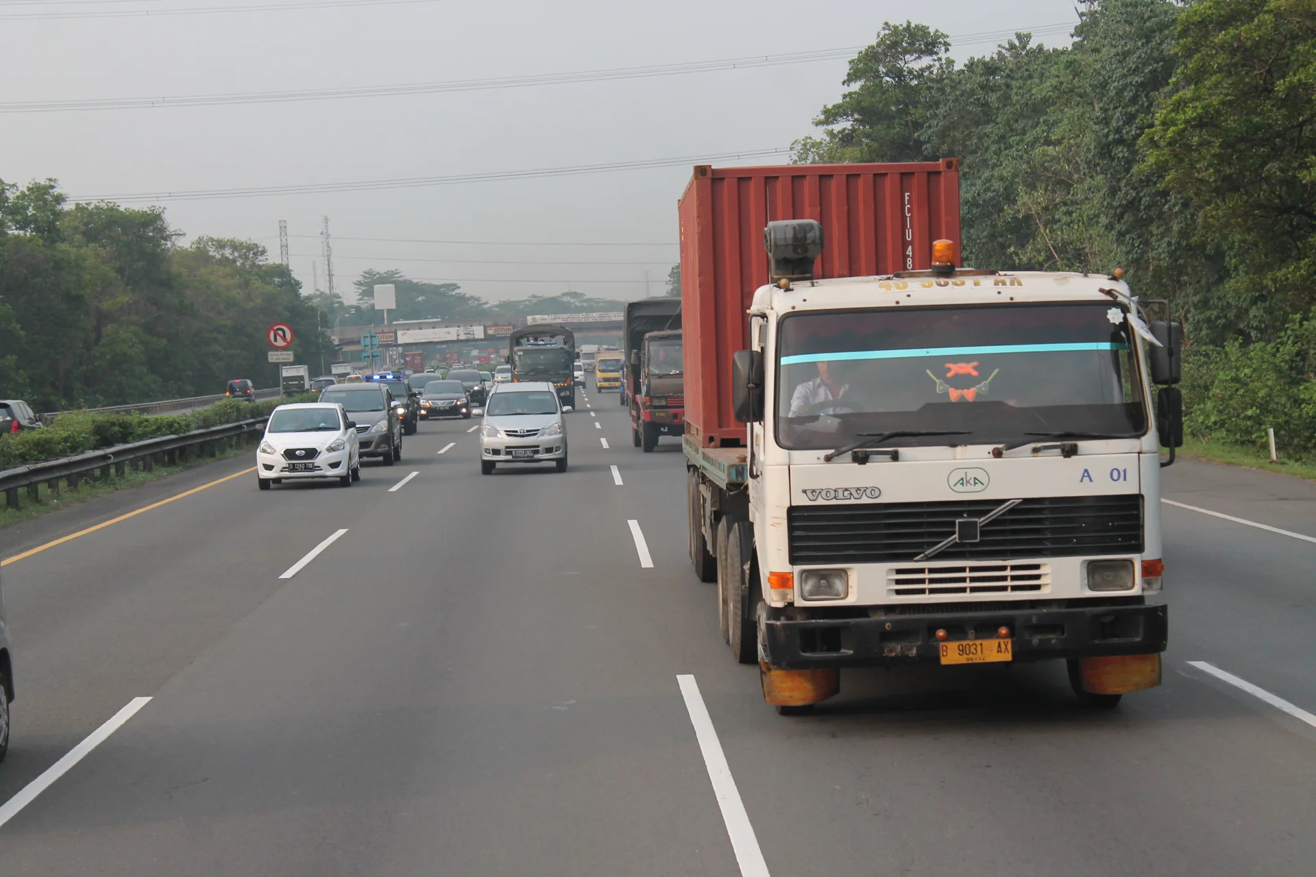 Truk trailer Volvo pengangkut kontainer merah melaju di Tol Jagorawi bersama mobil pribadi dan truk lain